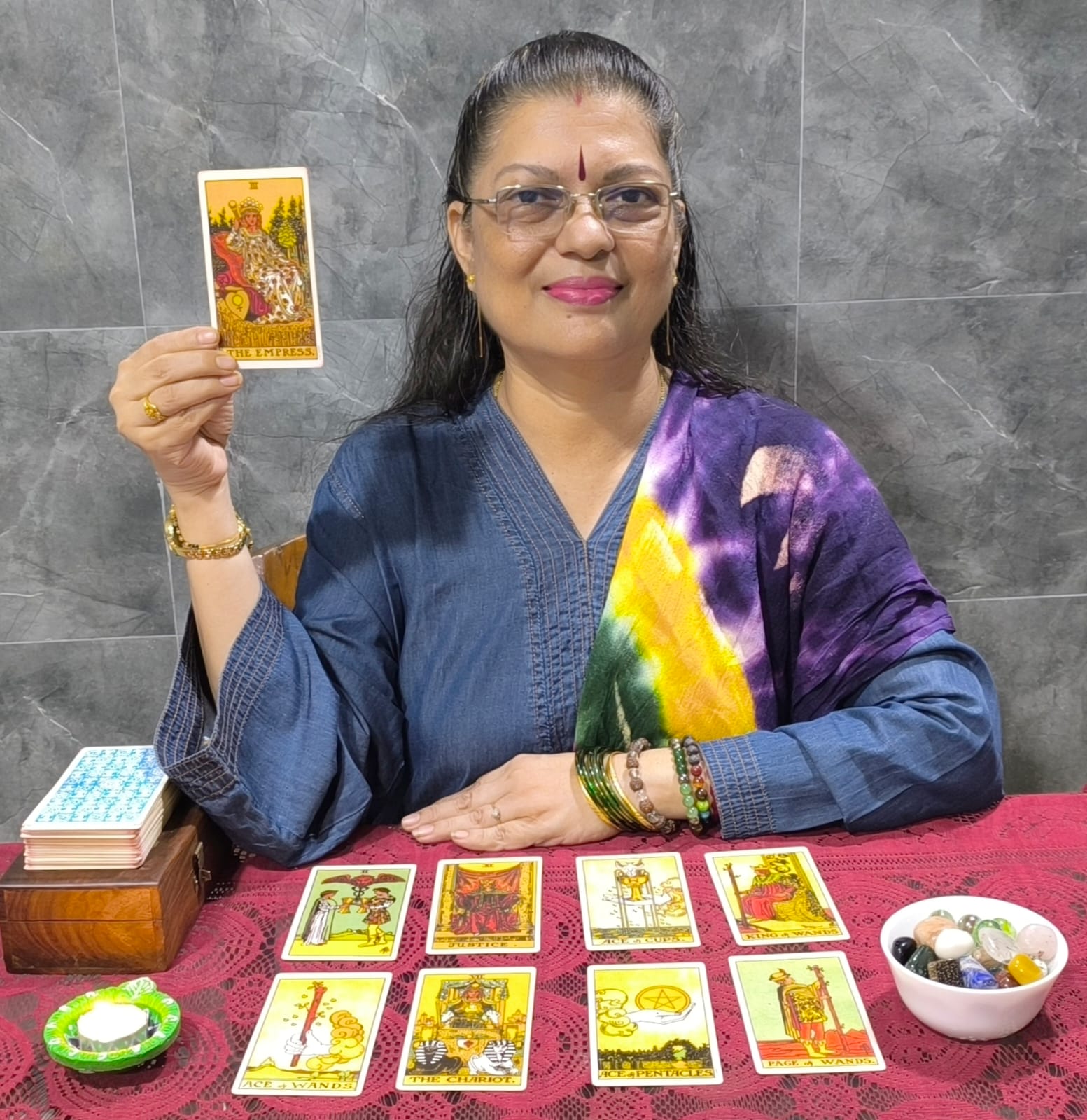 Rekha Rawatt holding The Empress tarot card with a card spread on the table